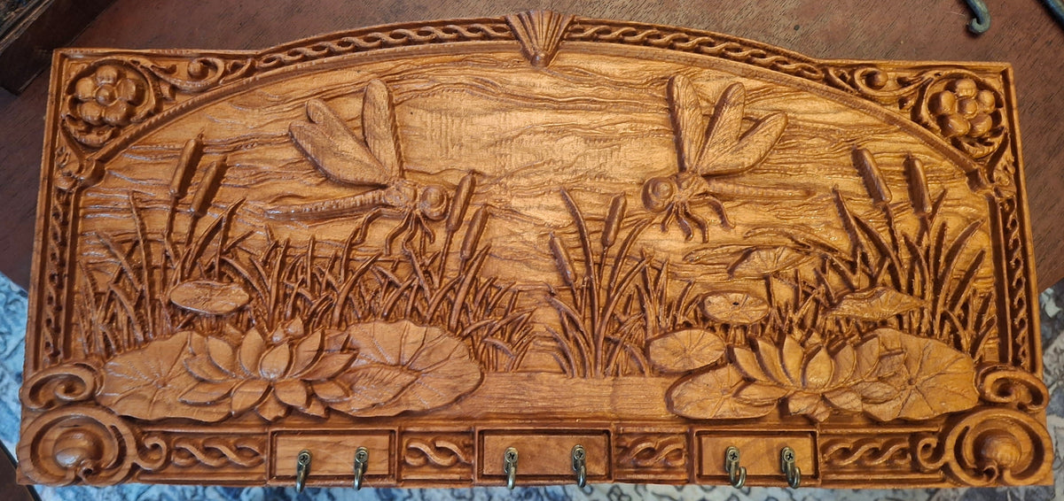 Dragonfly Pond Key Rack in honey oak – handcrafted wood with lotus and cattail relief carving and brass hooks